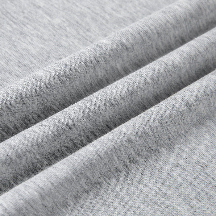 Close-up of light heather gray fabric with soft diagonal folds showing the knit texture.